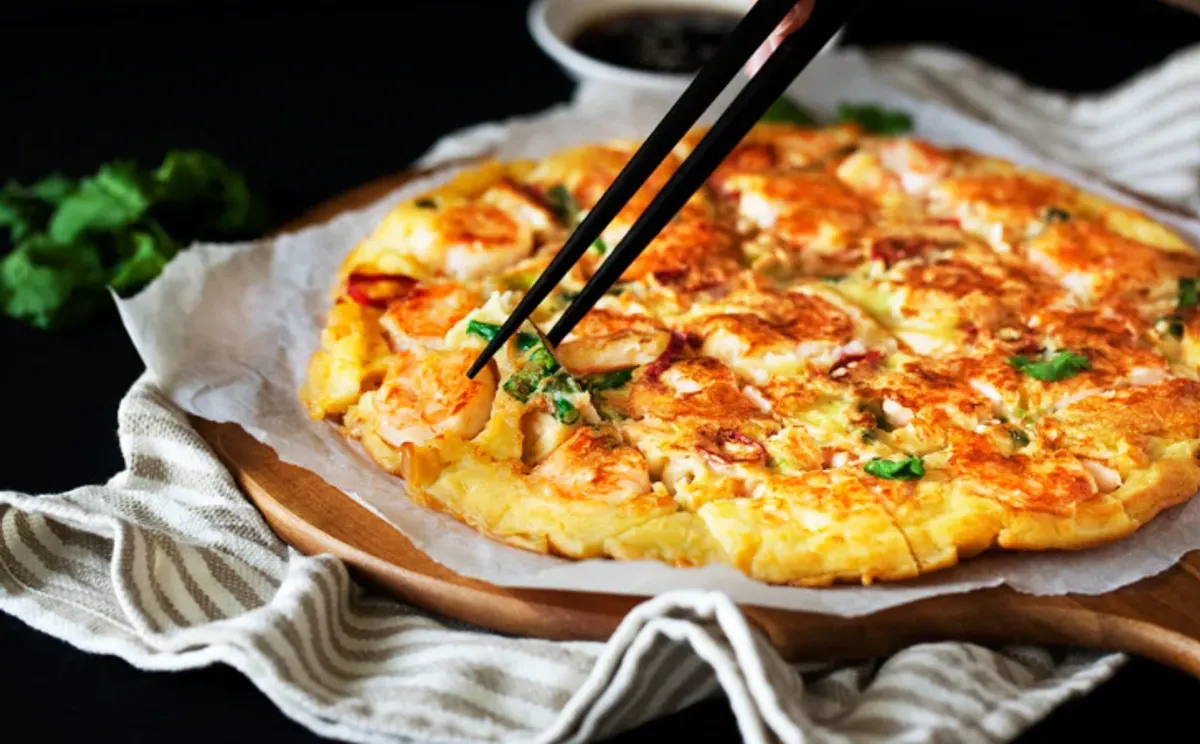 Seafood and green onion pancake being lifted from the pan